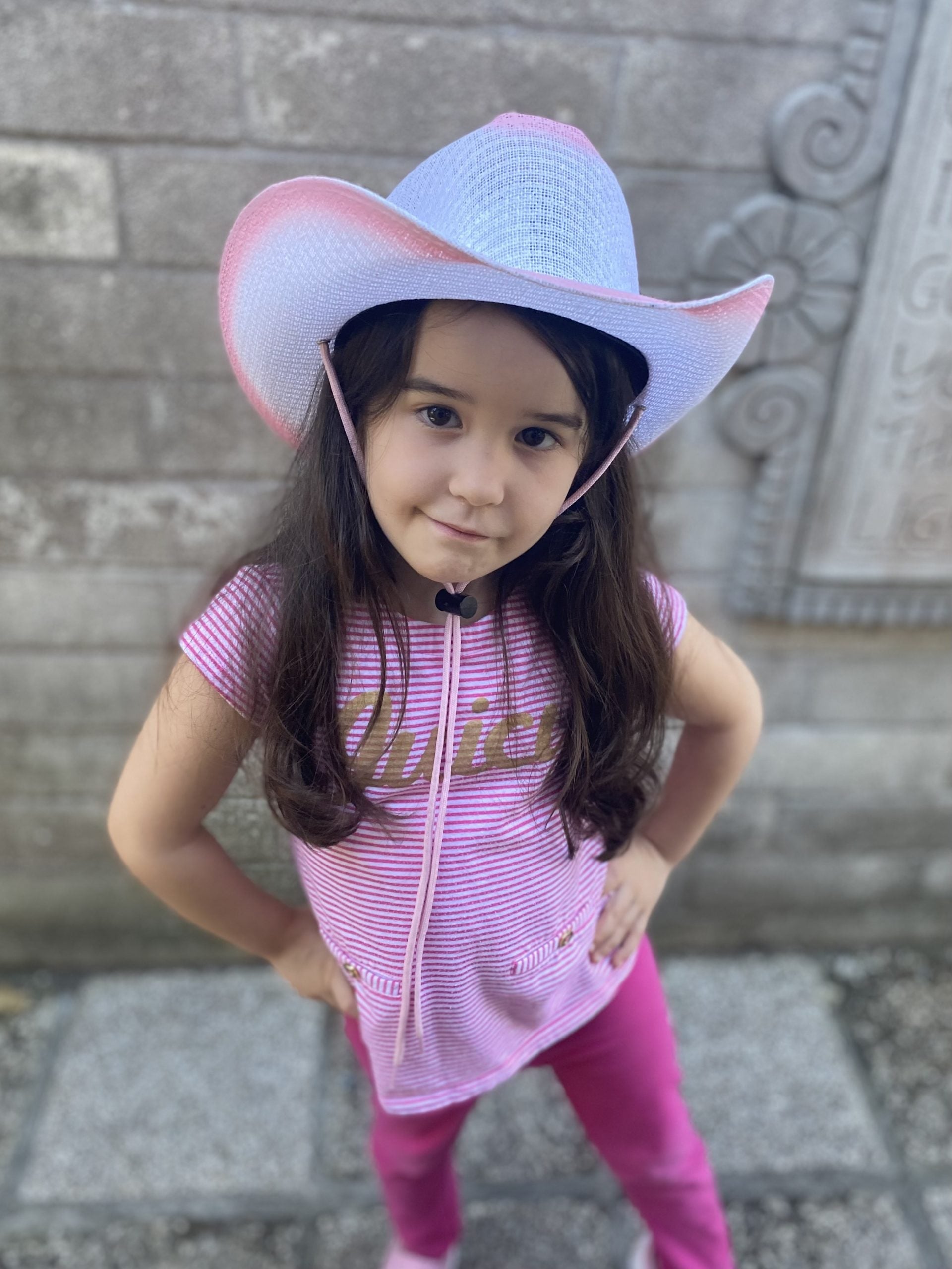 Little girl in a pink and white  cowgirl hat